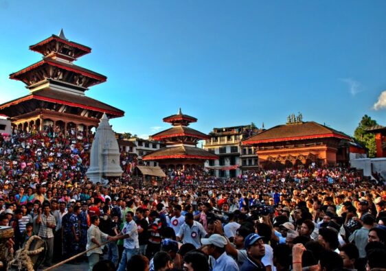 Large crowd gathered in Kathmandu Durbar Square surrounded by pagoda-style temples and a central stupa during a cultural festival.