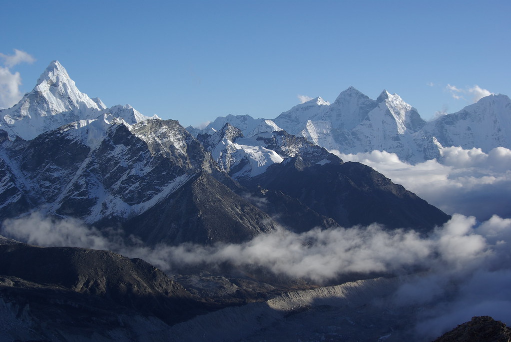“Snow‑covered Himalayan peaks with rocky ridges and misty valleys under clear blue sky”