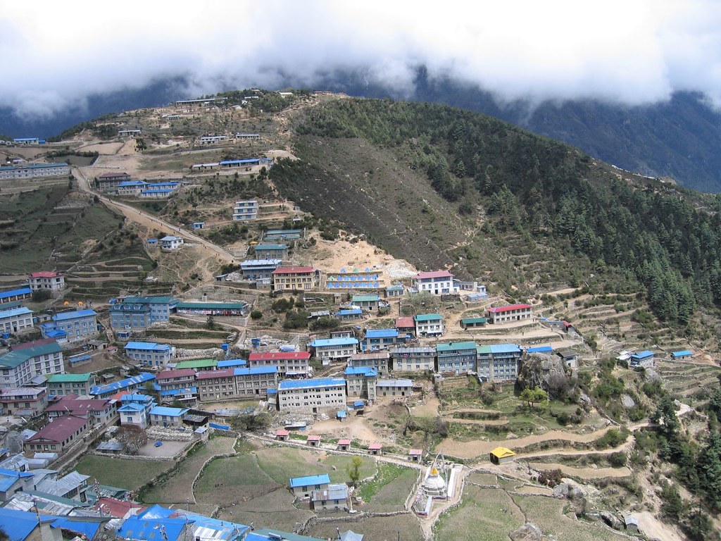 “Terraced Himalayan village with colorful roofs and misty mountain backdrop”
