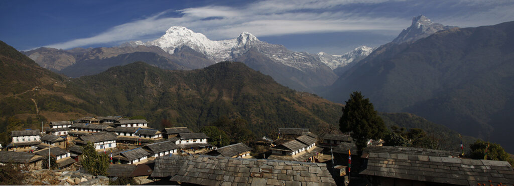 Himalayan stone village with terraced slopes and snowy peaks